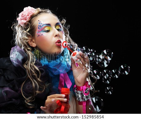 woman with creative make-up blowing soap bubbles.