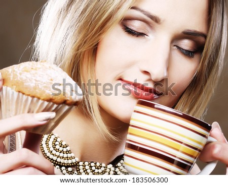Woman eating cookie and drinking coffee.