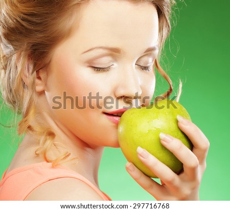 Young smiling sharming woman with green apple over green background