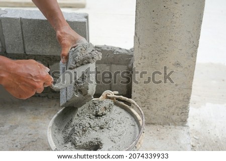 bricklayer scooping mixed mortar on brick to install bricks block on construction site, selective focus            Stockfoto © 