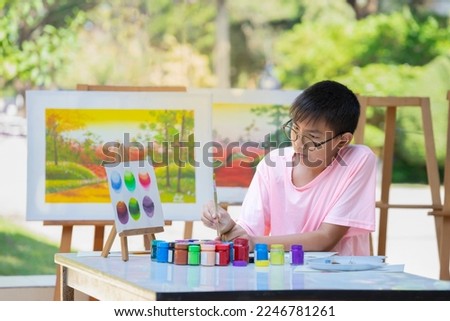 asian teenager boy wears eyeglasses thinking about comparison of primary colors while painting watercolor, drawing makes teens express their feelings and spark their creativity 