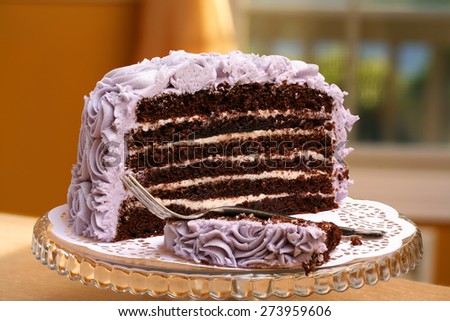 Deluxe 6 layer round chocolate butter cream cake with purple frosting and elegant glass stand