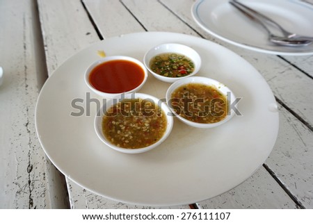 Thai dipping sauce in small bowl on white plate and white rustic table