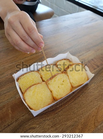 bread and butter toast in the paper box on timber table with human hand