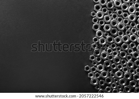 Metal nuts on dark background. Chromed screw nuts isolated. Steel nuts pattern. Set of Nuts and bolts. Tools for work. Black and white