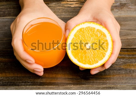 Slice of fresh Navel orange fruit and juice are holding by hand on wooden background,healthy food