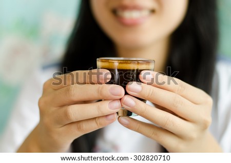 The cup of coffee (espresso) is holding by woman hand