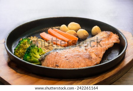 fried salmon steaks on hot pan and vegetable