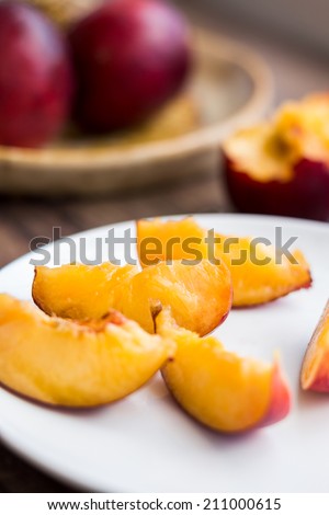 bright peach with a piece of wood on a wooden background, close up