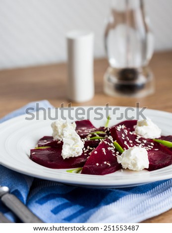 roasted beet salad with goat cheese and sesame seeds, snack on a white plate