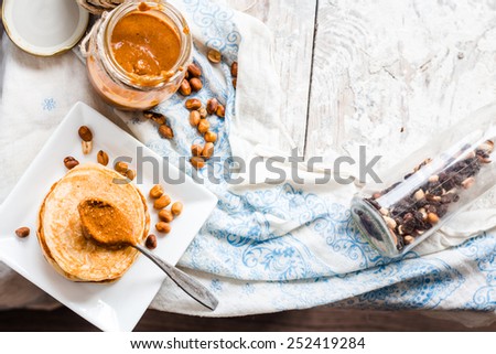 peanut butter in a jar, fresh peanuts and pancakes, top view and place for text