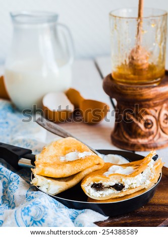 sweet pancakes with cottage cheese, prunes, honey and sour cream, rustic, in a frying pan