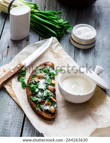rye bread with wild garlic, sour cream and quail eggs and beans appetizer, on a gray board