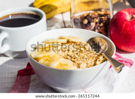 oatmeal with bananas, apples, nuts and dried fruit jar, cup of coffee, healthy breakfast