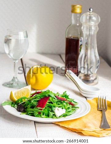 light green salad with arugula, beets, goat cheese and prunes, organic food on a white background