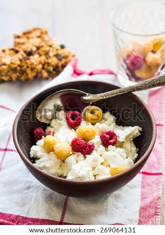 cottage cheese with fresh raspberries in a clay plate, granola bars, healthy food