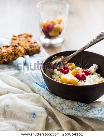 cottage cheese with fresh raspberries in a clay plate, granola bars, healthy food