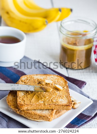 crispy toast with peanut butter, bananas, coffee, breakfast on a wooden background