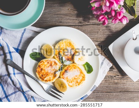 pancakes from cottage cheese  with banana, powdered sugar and fresh mint, gray wooden background, breakfast,top view