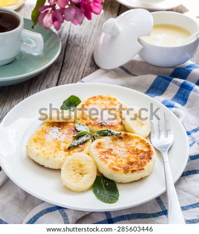 pancakes from cottage cheese  with banana, powdered sugar and fresh mint, gray wooden background, breakfast