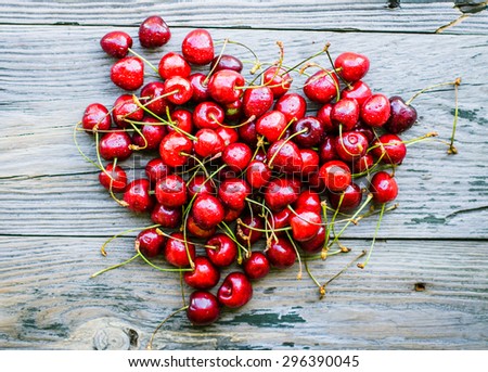 fresh red cherry in a plate on a gray wood background,\
healthy snack, summer berries,heart, top view