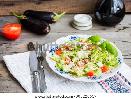 Fresh vegetable salad with tomato, eggplant, sesame seeds and flax, rustic background
