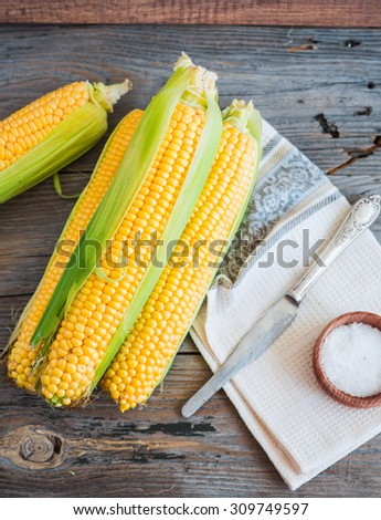 Fresh corn on cobs on a wooden surface, whole plant foods, top view, clean eating