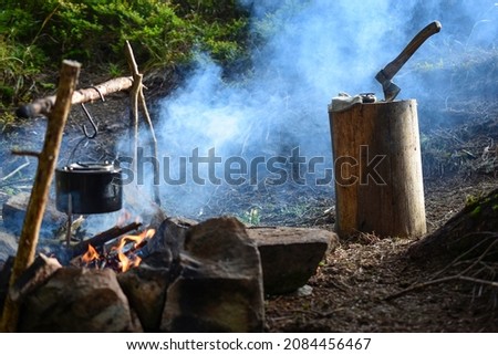 Wooden stump with an ax in blue smoke and a fire pit with a sooty cauldron Foto stock © 