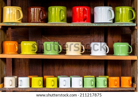 many types of colorful cups on wooden shelf