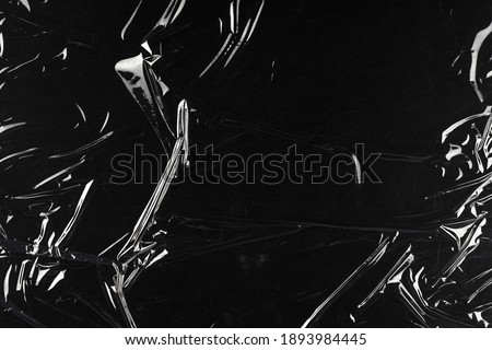 Transparent plastic wrap on the black background. Clean blank texture overlay effect template. Isolated wrinkle surface branding mock-up.