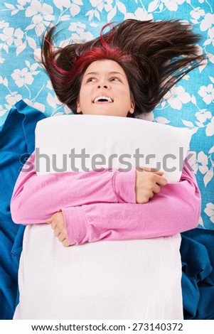 Joyful hugging for good morning. Young girl in pyjamas on her bed.