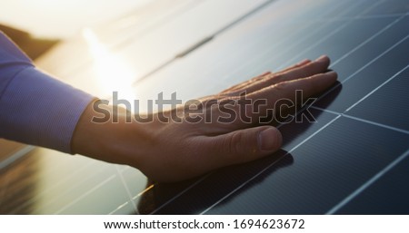 Close up of an young engineer hand is checking an operation of sun and cleanliness of photovoltaic solar panels on a sunset. Concept:renewable energy, technology,electricity,service, green,future Stockfoto © 