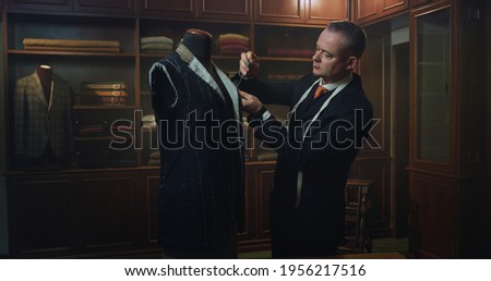 Cinematic shot of professional tailor taking measurements for creation of custom high quality tailored suit in luxury tailoring atelier.Concept of fashion, handmade, hand craft, couturier and business