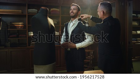Cinematic shot of professional tailor taking measurements of client for creation custom tailored suit in a luxury tailoring atelier. Concept of fashion, handmade, hand craft, couturier and business Stock foto © 