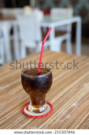Cola drink with a straw in a glass of red on the table in a bar or restaurant
