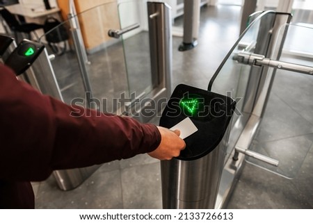 Close up of unrecognizable swiping card passing turnstile to enter building. The hand holds the card. Access is allowed. Сток-фото © 