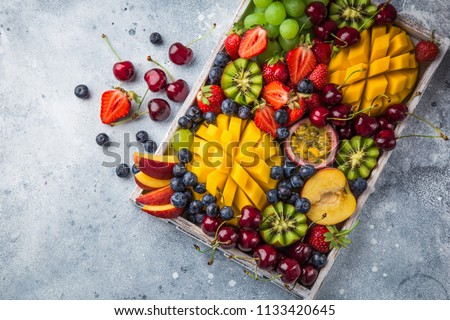 delicious fruits and berries platter.  Mango, kiwi, strawberry, grape, cherry, blueberry, peach and passion fruit on wooden tray, top view, copy space ストックフォト © 