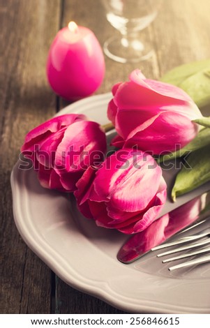 Spring table setting with three pink tulips and candle egg for Easter, toned