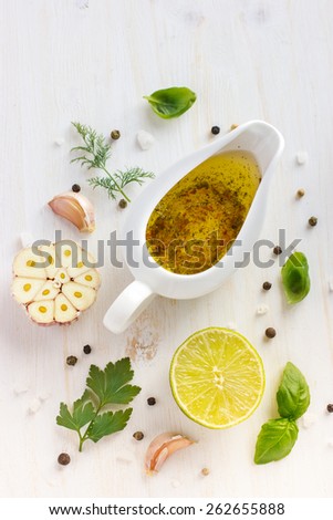 Ingredients for salad dressing. Olive oil, garlic, lemon, herbs and spices on white background, top view