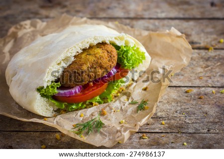 falafel with fresh vegetables in pita bread on wooden background