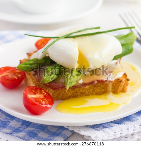 Eggs Benedict with hollandaise sauce on toast with  bacon and asparagus, selective focus, square image