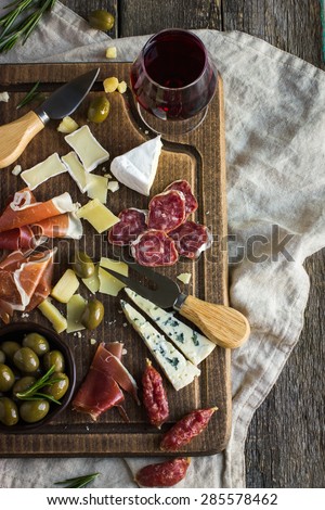 Assortment of various types of cheese and meat on wooden board, top view