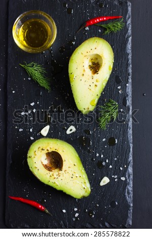 avocado with olive oil and spices on black background