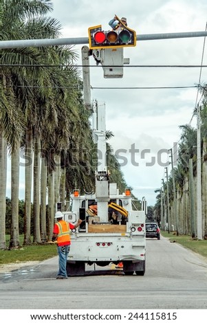 MIAMI, FLORIDA - January 13, 2015: Electrical workers are busy repairing a broken traffic light on a busy intersection.