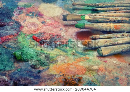 Paint brushes lie on the palette of paints