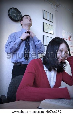 Sitting businesswoman and businessman corrects a tie