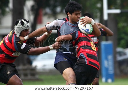 KUALA LUMPUR-MARCH 31: Two unidentified SAHOCA players try to tackle an UiTM Lions player during a Malaysian Rugby Union Super League 2012 match (UiTM Lions vs SAHOCA) on March 31, 2012 in Kuala Lumpur, Malaysia