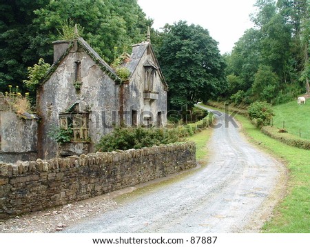 Old stone house, stone wall and winding road in County Cork, Ireland.