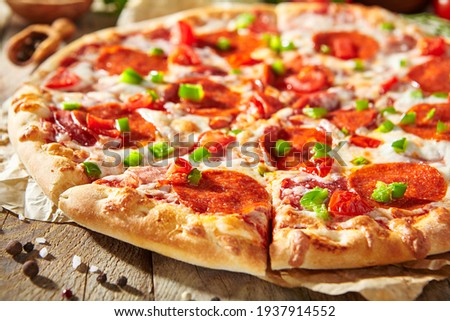 Pepperoni pizza with pizza sauce, mozzarella cheese and pepperoni. Pizza on wooden board on wood table with ingredients