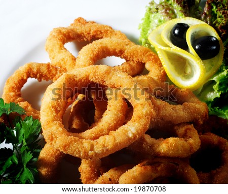 Seafood - Fried Calamari. Deep-fried Squid Dressed with Salad Leaves, Parsley, Olives and Lemon